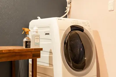 a white washing machine sitting next to a wooden table at \u6674\u30ec\u5c4b \u65b0\u8fb0\u7f8e\u8358 Hareya Shin-Tatsumiso in Tokyo