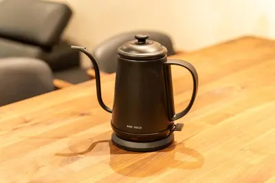 a black tea kettle sitting on a wooden table at \u6674\u30ec\u5c4b \u7b51\u6ce2\u8358 Hareya Tsukubaso in Tokyo