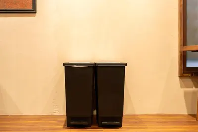 a black trash can sitting next to a wall at \u6674\u30ec\u5c4b \u7b51\u6ce2\u8358 Hareya Tsukubaso in Tokyo