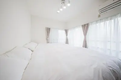 a white bed in a bedroom with a window at \u5317\u5c0f\u5ca9\u6238\u5efa in Tokyo