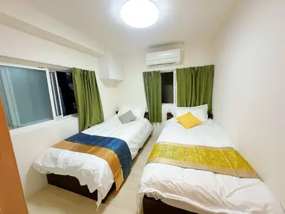 two beds in a room with green curtains at Ueno Sakura Inn \u4e0a\u91ce\u516c\u56ed in Tokyo