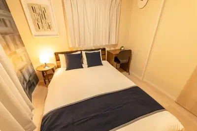 a bedroom with a large bed with two blue pillows at Hotel ITSUKI in Tokyo