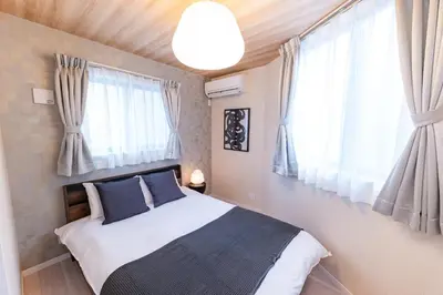 a bedroom with a bed with blue pillows and windows at Hotel ITSUKI in Tokyo