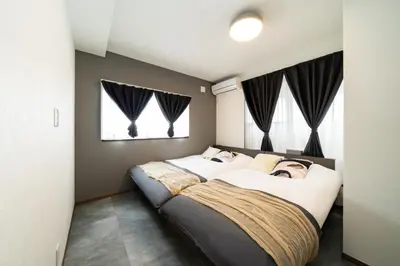 two beds in a bedroom with black curtains at 1, Horikiri Entire house for rent, \u5800\u5207 in Tokyo