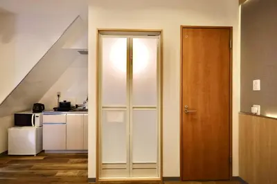 a kitchen with white cabinets and a wooden door at \u696d\u5e731\u968e \u30b9\u30ab\u30a4\u30c4\u30ea\u30fc\u30d3\u30e5\u30fc \u99c5\u8fd1 \u6700\u59273\u540d in Tokyo