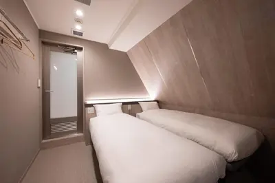 two beds in a small room with a window at EISEI STAY Ikebukuro Nishi in Tokyo