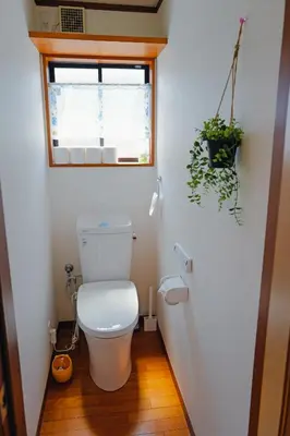 a bathroom with a toilet with a window and a plant at Akira Hiro House - Room102 in Tokyo