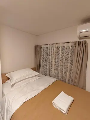 a bedroom with a bed with white sheets and a window at THE ONE kouennji in Tokyo