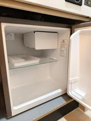 an empty refrigerator with its door open in a kitchen at THE ONE kouennji in Tokyo