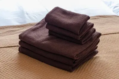 a pile of towels sitting on top of a bed at House Hotel Shinnakano 202 in Tokyo