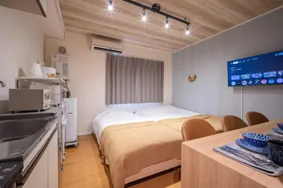 a room with two beds and a table with chairs at House Hotel Shinnakano 202 in Tokyo