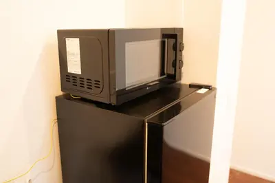 a microwave sitting on top of a black refrigerator at Poka Premium Kuramae \u6696\u5bbf\u8535\u524d in Tokyo