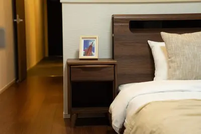 a nightstand with a picture on it next to a bed at Poka Premium Kuramae \u6696\u5bbf\u8535\u524d in Tokyo