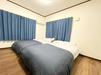 two beds in a room with blue curtains at Amazing location Harajuku House Shibuya 8pepl 2BR in Tokyo