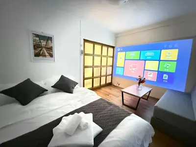 a room with two beds and a large screen at Shinjuku Waseda D2 in Tokyo