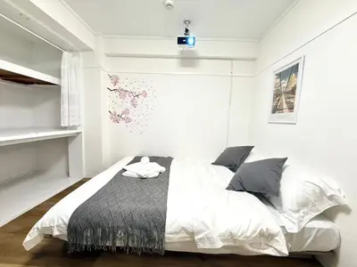 a bedroom with a white bed with a black blanket at Shinjuku Waseda D2 in Tokyo