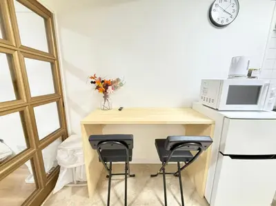 a kitchen with a table with two chairs and a microwave at Shinjuku Waseda Cartref 3 in Tokyo