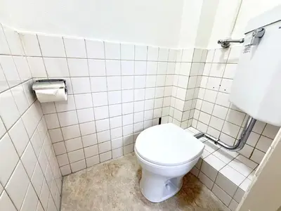 a bathroom with a toilet in a white tiled room at Shinjuku Waseda Cartref 3 in Tokyo
