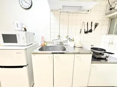 a white kitchen with a sink and a microwave at Shinjuku Waseda Cartref 3 in Tokyo