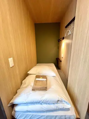 a small room with a bed with a book on it at Otemachi Kamon Hotel in Tokyo