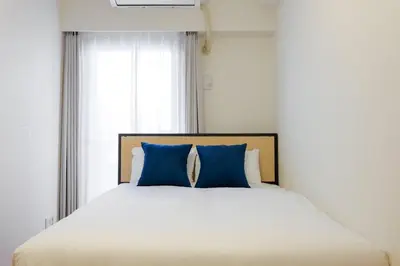 a bed with blue pillows in a room with a window at \u30d7\u30e9\u30c1\u30ca\u30b3\u30fc\u30c8\u5357\u9ebb\u5e03 in Tokyo