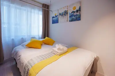 a bedroom with a bed with yellow pillows and a window at NDZ102 3 min walk to station, 2 lines, Yamanote Line, explore Tokyo, high-speed Wi-Fi in Tokyo