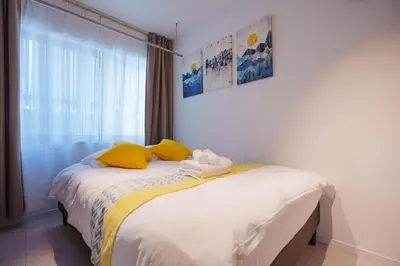 a bedroom with a bed with yellow pillows and a window at NDZ102 3 min walk to station, 2 lines, Yamanote Line, explore Tokyo, high-speed Wi-Fi in Tokyo