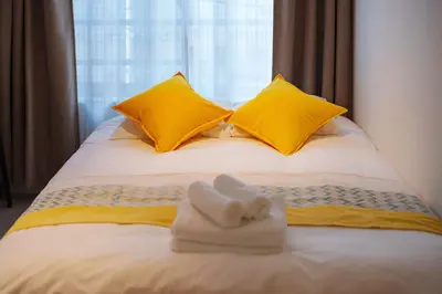a bedroom with yellow pillows and towels on a bed at NDZ302 3 min walk to the station, 2 lines, Yamanote Line, explore Tokyo, high-speed Wi-Fi in Tokyo