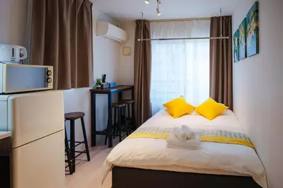 a small room with a bed with yellow pillows at NDZ302 3 min walk to the station, 2 lines, Yamanote Line, explore Tokyo, high-speed Wi-Fi in Tokyo