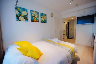 a bedroom with a bed with yellow pillows at NDZ302 3 min walk to the station, 2 lines, Yamanote Line, explore Tokyo, high-speed Wi-Fi in Tokyo
