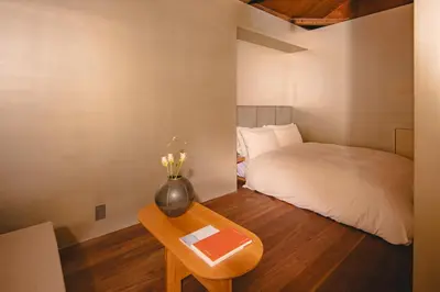 a bedroom with a bed and a table with a vase at MU HEN KO Tokyo in Tokyo