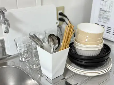 a kitchen counter with plates and utensils and a sink at Shinjuku Waseda C4 in Tokyo