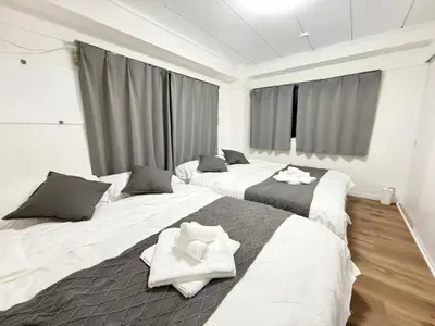 a room with three beds with towels on them at Shinjuku Waseda C4 in Tokyo