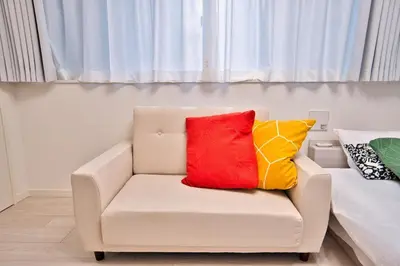 a white chair with two colorful pillows on it at Mjk 201 8min Inaricho 11min Ueno Max 3 in Tokyo