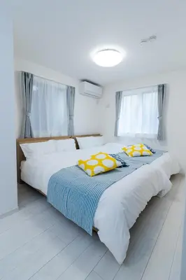 two beds with yellow and blue sheets in a bedroom at Oasis IKEBUKURO in Tokyo