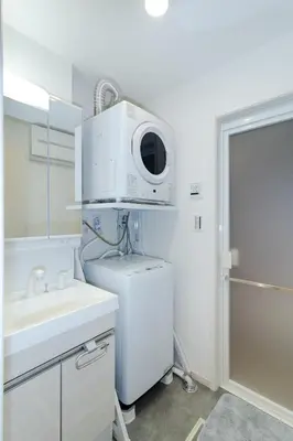 a white bathroom with a microwave on top of a refrigerator at Oasis IKEBUKURO in Tokyo
