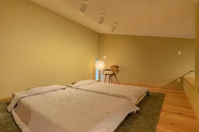 a bedroom with a bed and a chair in it at Cozy 65m2 Apartment including 20m2 Loft for one month stay and longer in Tokyo