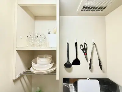 a kitchen cabinet with plates and utensils in it at Shinjuku \u9ad8\u7530\u99ac\u5834\u30c6\u30e9\u30ce\u30d0B5 in Tokyo