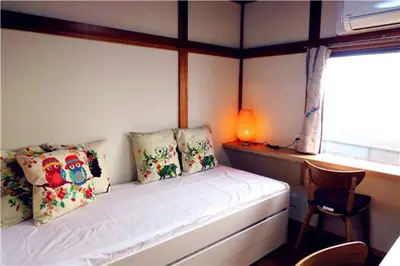 a bedroom with a bed and a chair and a window at KIKI House2 in Tokyo