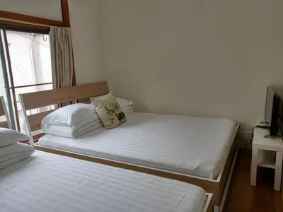 two twin beds in a room with a window at KIKI House2 in Tokyo
