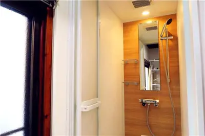 a bathroom with a shower and a mirror at KIKI House2 in Tokyo