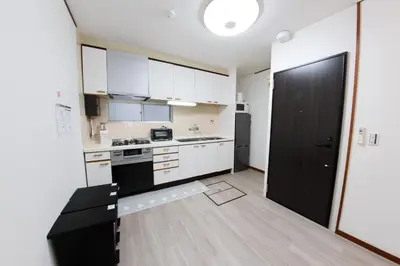 a kitchen with white cabinets and a black door at \u30cf\u30a4\u30af\u30ec\u30b9\u30c8\u65b0\u4e2d\u91ce in Tokyo