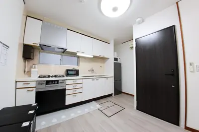 a kitchen with white cabinets and a black door at \u30cf\u30a4\u30af\u30ec\u30b9\u30c8\u65b0\u4e2d\u91ce in Tokyo