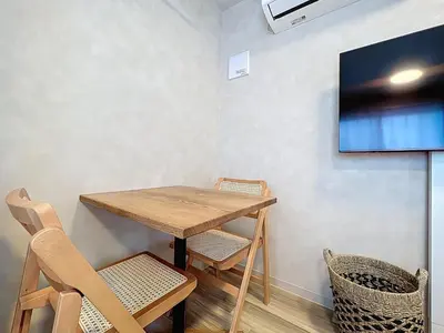 a wooden table and chairs with a television on a wall at Viento Ikebukuro in Tokyo