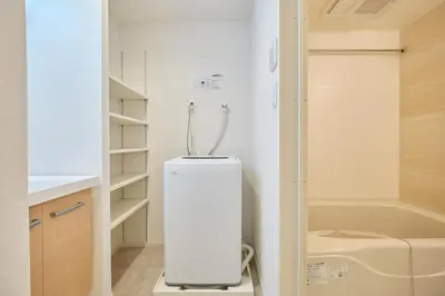 a small white refrigerator in a bathroom with a bath tub at monthly akebonobashi in Tokyo