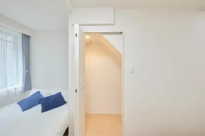 a bedroom with a bed with blue pillows and a mirror at monthly akebonobashi in Tokyo