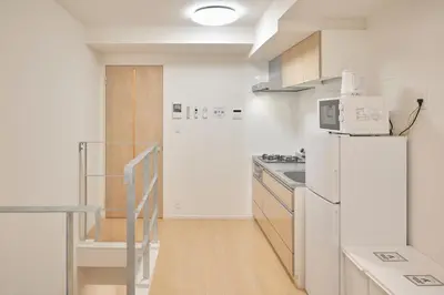 a kitchen with a white refrigerator freezer next to a door at monthly akebonobashi in Tokyo