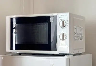 a microwave oven sitting on top of a refrigerator at \u671f\u9593\u9650\u5b9a \u6d45\u8349\u6a4b3floor in Tokyo