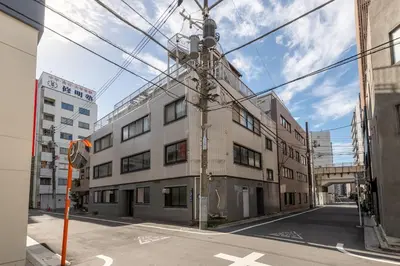 an empty street with an apartment building and power lines at \u671f\u9593\u9650\u5b9a \u6d45\u8349\u6a4b4floor in Tokyo