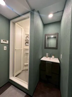a green bathroom with a sink and a refrigerator at Tokyo Manekineko Stay \u62db\u304d\u732b\u3067\u6709\u540d\u306a\u8c6a\u5fb3\u5bfa\u99c5\u304b\u3089\u5f92\u6b699\u5206 \u30a2\u30fc\u30c6\u30a3\u30b9\u30c8\u5236\u4f5c\u306e\u62db\u304d\u732b\u30d9\u30c3\u30c9\u306e\u4e2d\u306b\u6cca\u307e\u308c\u308b\u5bbf in Tokyo